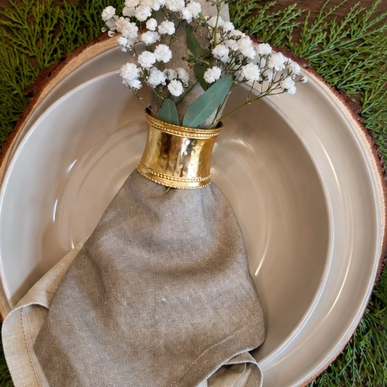 A linen napkin in a gold ring with baby's breath on a stoneware bowl at Tiff's table.